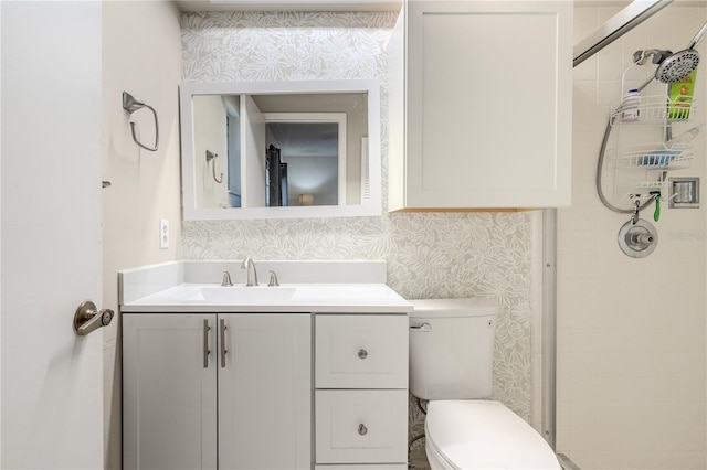 bathroom with tiled shower, vanity, and toilet