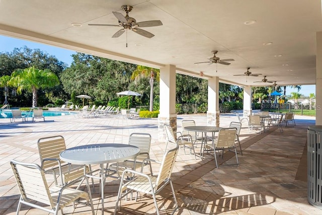 view of patio with ceiling fan, a playground, and a community pool