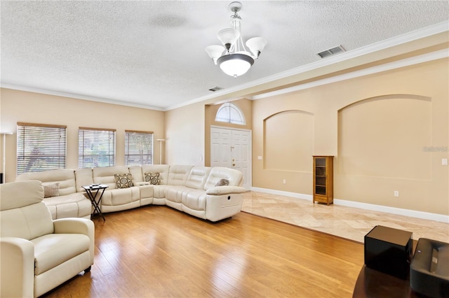 living room featuring crown molding, a chandelier, a textured ceiling, and light hardwood / wood-style floors