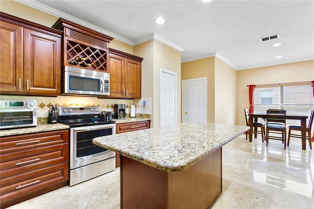 kitchen with appliances with stainless steel finishes, a textured ceiling, and a kitchen island