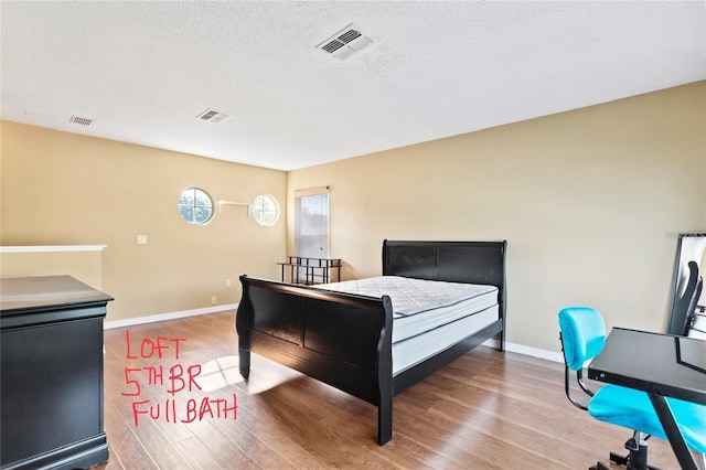 bedroom featuring wood-type flooring and a textured ceiling