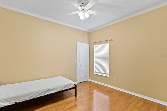 bedroom featuring wood-type flooring, a textured ceiling, ceiling fan, and crown molding