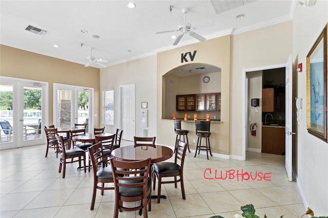 tiled dining room featuring ceiling fan, indoor wet bar, and ornamental molding