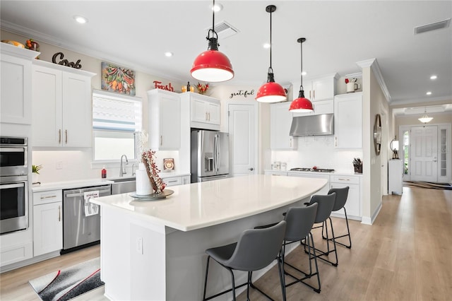 kitchen featuring white cabinetry, appliances with stainless steel finishes, hanging light fixtures, and a kitchen island