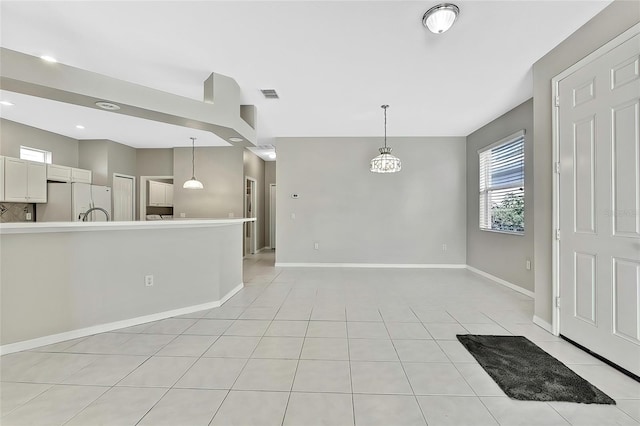 interior space featuring decorative light fixtures, an inviting chandelier, light tile patterned floors, and white fridge with ice dispenser