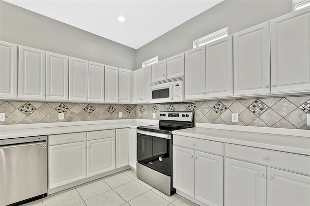 kitchen with stainless steel appliances, light tile patterned floors, and white cabinets