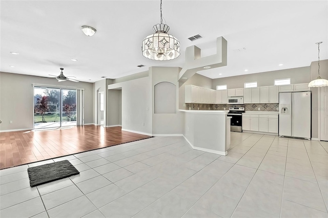 kitchen featuring white appliances, pendant lighting, light tile patterned floors, decorative backsplash, and white cabinetry