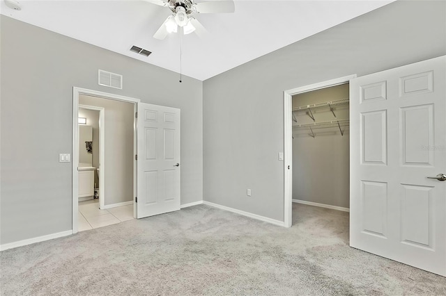 unfurnished bedroom featuring ceiling fan, light colored carpet, a spacious closet, and a closet