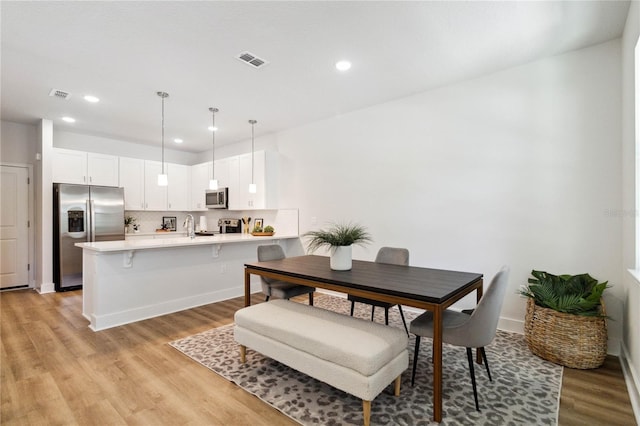 dining space featuring light wood-type flooring and sink