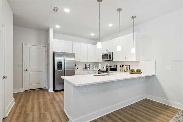 kitchen with decorative light fixtures, stainless steel appliances, white cabinetry, and sink