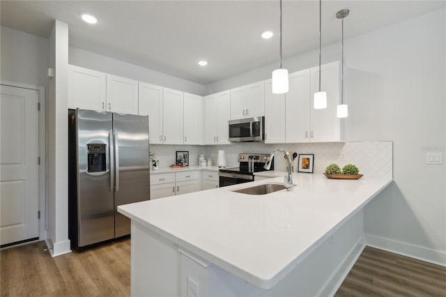 kitchen with kitchen peninsula, white cabinets, stainless steel appliances, and decorative light fixtures