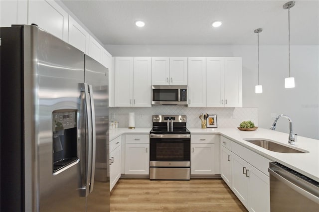 kitchen featuring white cabinets, appliances with stainless steel finishes, and pendant lighting