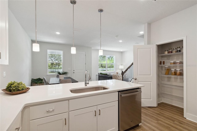 kitchen featuring dishwasher, white cabinetry, sink, and hanging light fixtures