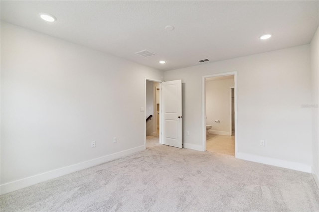 unfurnished bedroom featuring ensuite bath and light colored carpet