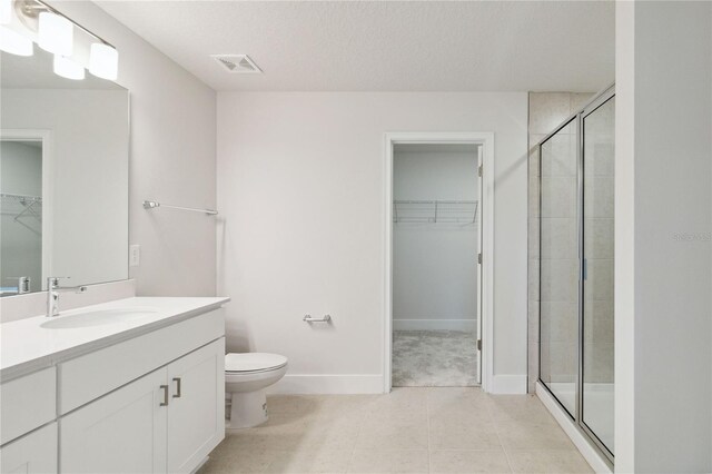 bathroom with tile patterned floors, a textured ceiling, vanity, toilet, and a shower with shower door