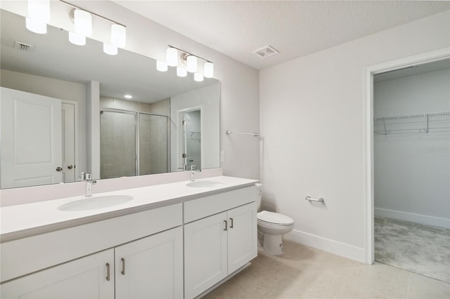 bathroom featuring vanity, toilet, a shower with shower door, and a textured ceiling