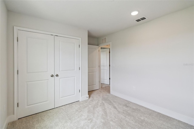 unfurnished bedroom featuring light colored carpet and a closet