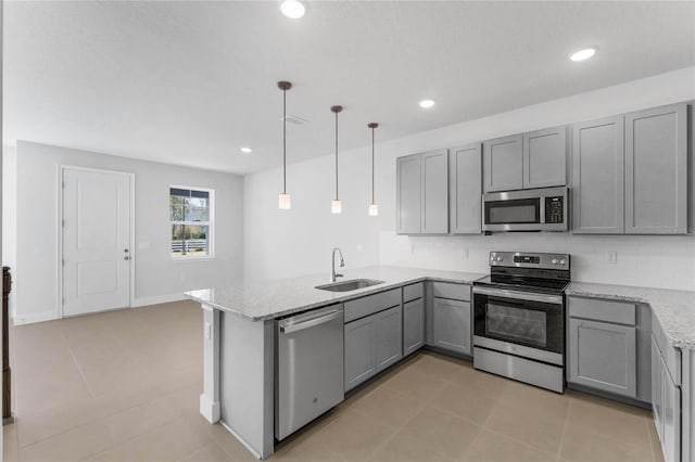 kitchen with kitchen peninsula, appliances with stainless steel finishes, light stone counters, sink, and hanging light fixtures