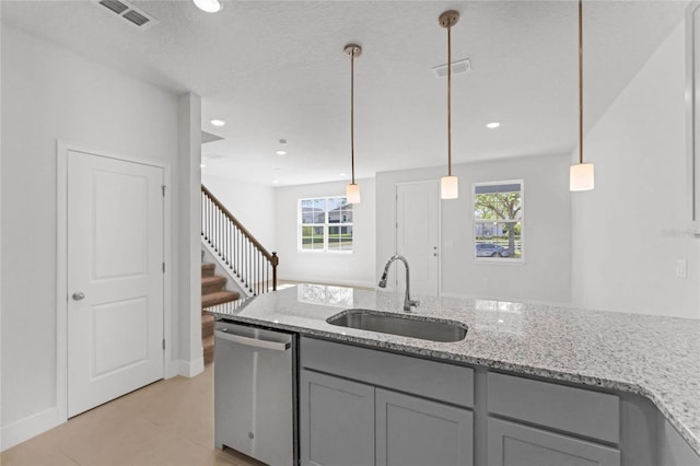 kitchen with light stone counters, gray cabinetry, sink, pendant lighting, and dishwasher