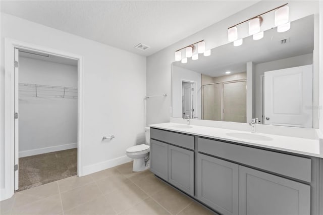 bathroom with vanity, tile patterned flooring, toilet, a textured ceiling, and walk in shower