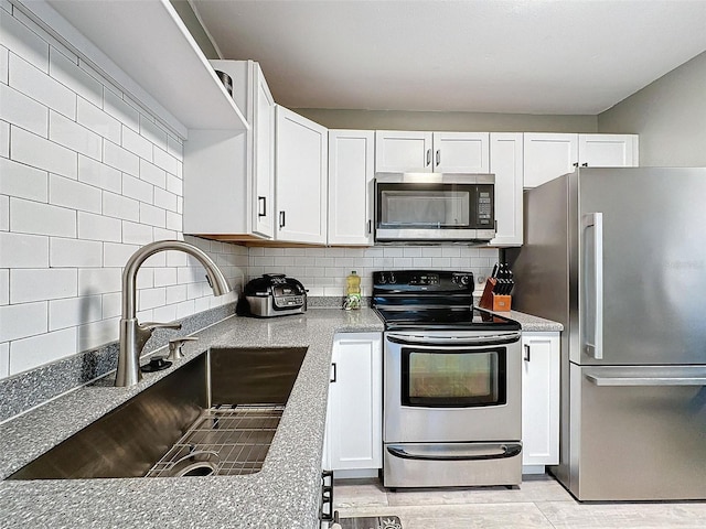 kitchen featuring decorative backsplash, appliances with stainless steel finishes, light stone countertops, sink, and white cabinets