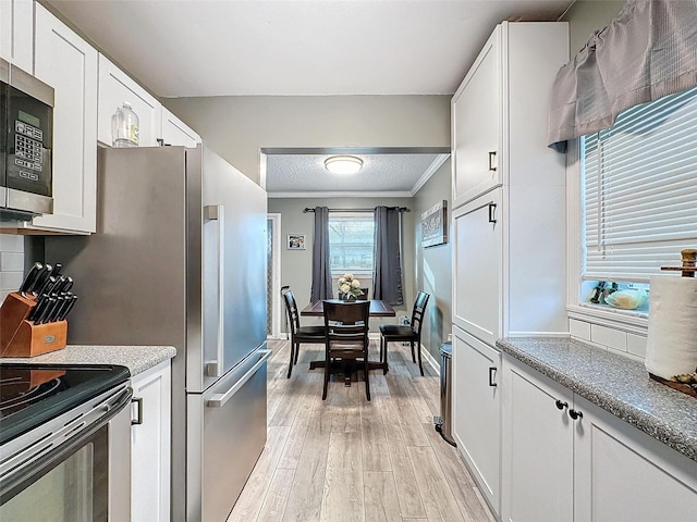 kitchen with backsplash, crown molding, light wood-type flooring, white cabinetry, and stainless steel appliances