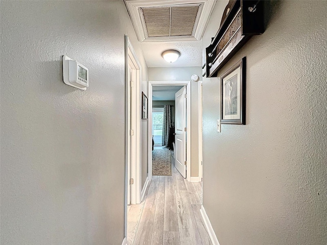 corridor with a textured ceiling and light wood-type flooring