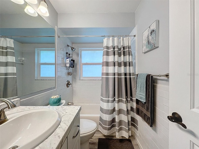 full bathroom with vanity, toilet, shower / bathtub combination with curtain, and tile walls