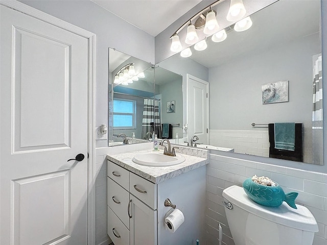 bathroom featuring vanity, toilet, and tile walls