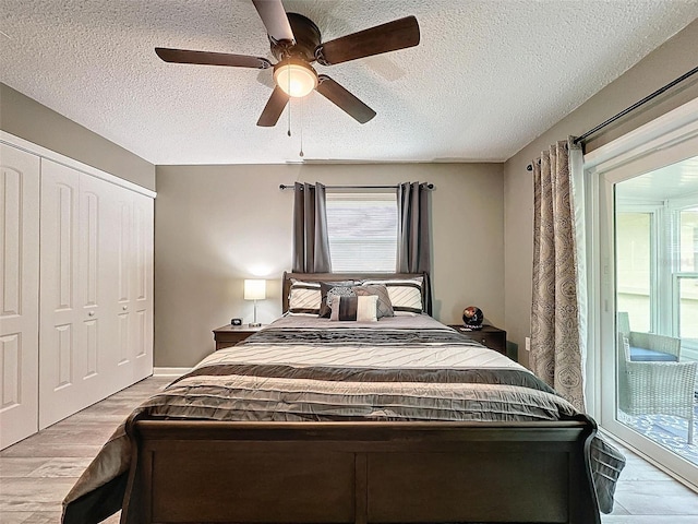 bedroom with light hardwood / wood-style flooring, ceiling fan, access to exterior, a textured ceiling, and a closet