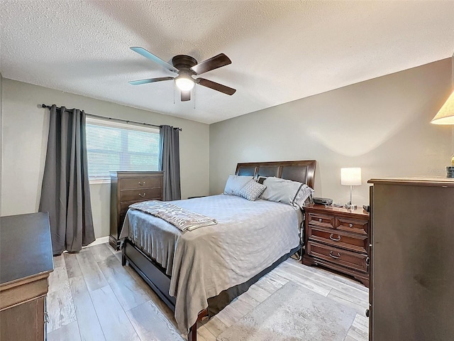 bedroom featuring ceiling fan, light hardwood / wood-style floors, and a textured ceiling