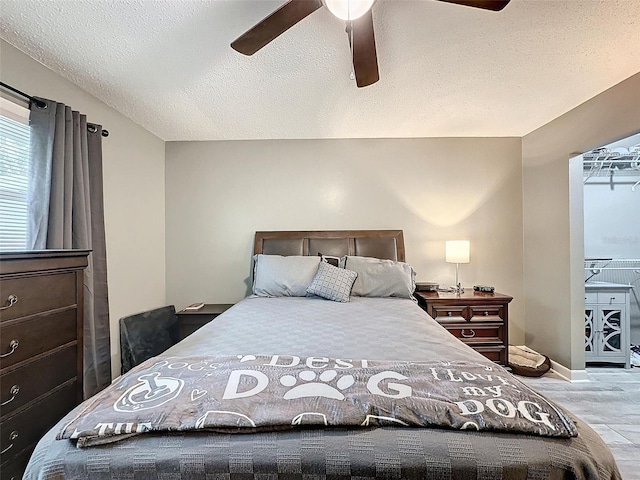 bedroom with a textured ceiling, light hardwood / wood-style floors, and ceiling fan