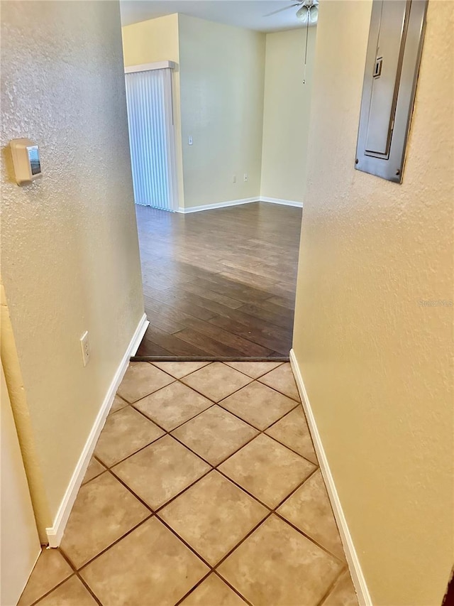 hall featuring light tile patterned floors and electric panel