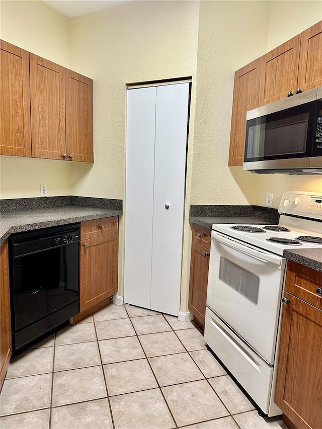 kitchen featuring white electric range oven, dishwasher, and light tile patterned flooring