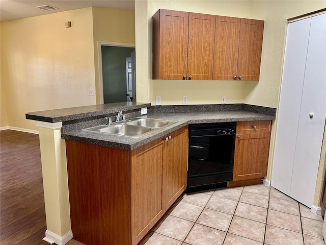 kitchen featuring kitchen peninsula, sink, light tile patterned floors, and black dishwasher