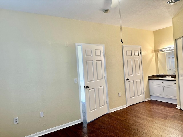 unfurnished bedroom featuring ensuite bathroom, dark hardwood / wood-style floors, ceiling fan, and sink