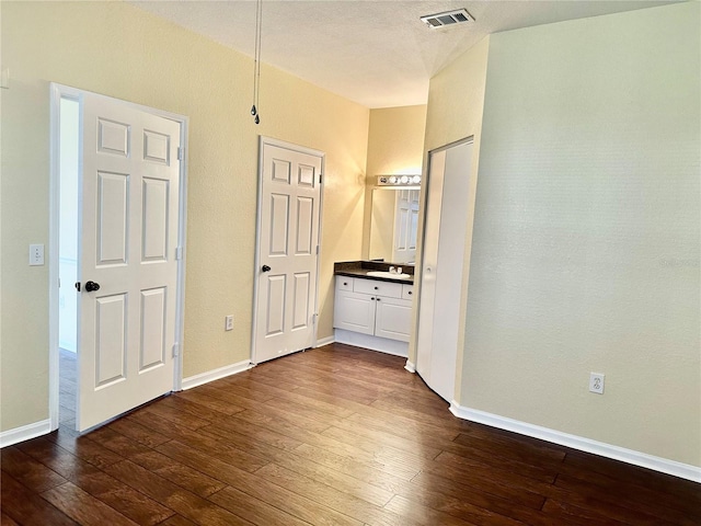 unfurnished bedroom featuring connected bathroom, sink, and dark wood-type flooring