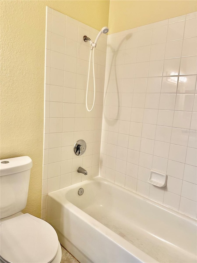 bathroom featuring toilet and tiled shower / bath