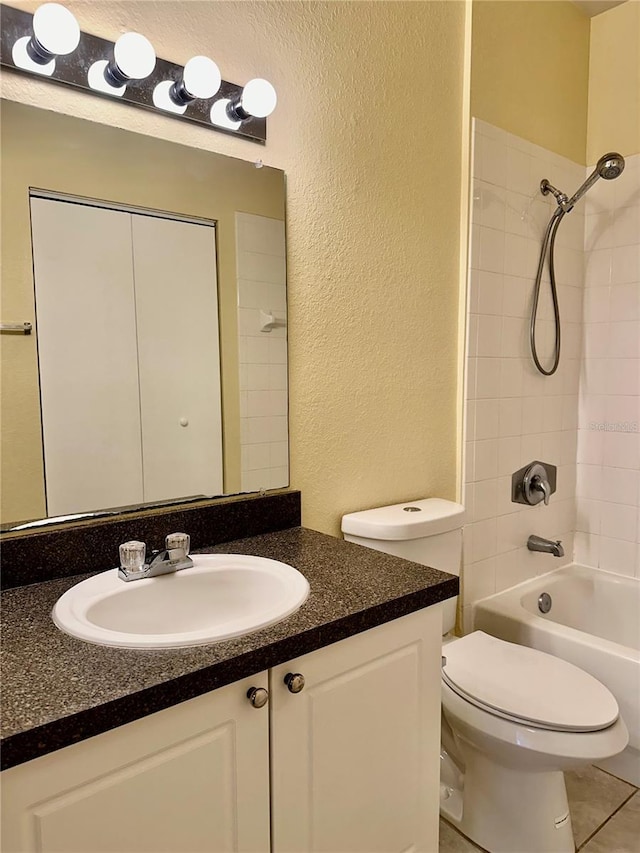 full bathroom with tiled shower / bath, tile patterned flooring, vanity, and toilet