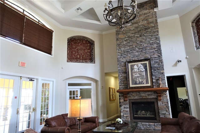 living room with french doors, ornamental molding, a towering ceiling, a fireplace, and a notable chandelier