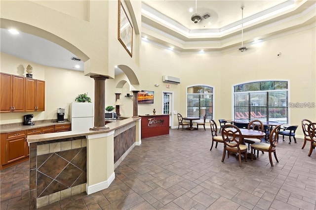 kitchen with white fridge, a high ceiling, a wall mounted air conditioner, and ornamental molding