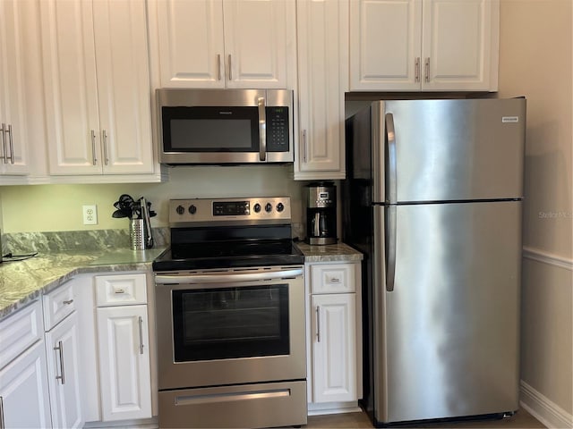 kitchen with light stone counters, white cabinetry, and stainless steel appliances