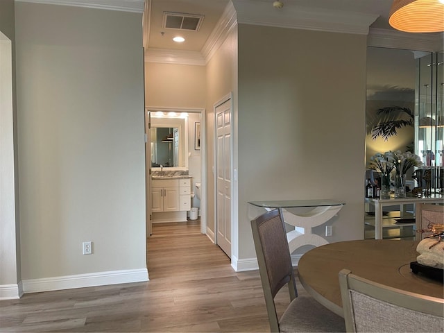 dining space with light hardwood / wood-style flooring, crown molding, and sink