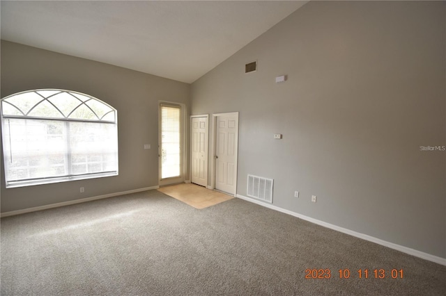 spare room featuring light carpet and high vaulted ceiling