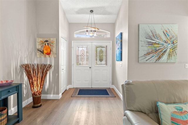 foyer entrance featuring an inviting chandelier, a textured ceiling, and hardwood / wood-style flooring