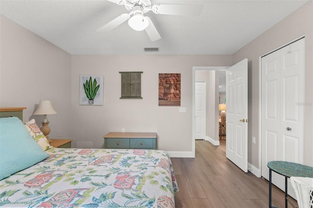 bedroom featuring ceiling fan, light wood-type flooring, a textured ceiling, and a closet