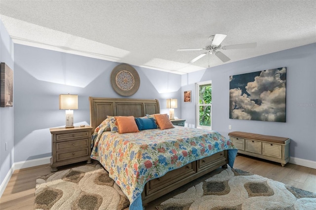 bedroom with ceiling fan, light hardwood / wood-style floors, and a textured ceiling