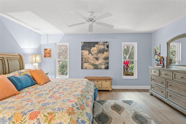 bedroom with a textured ceiling, light hardwood / wood-style flooring, and ceiling fan