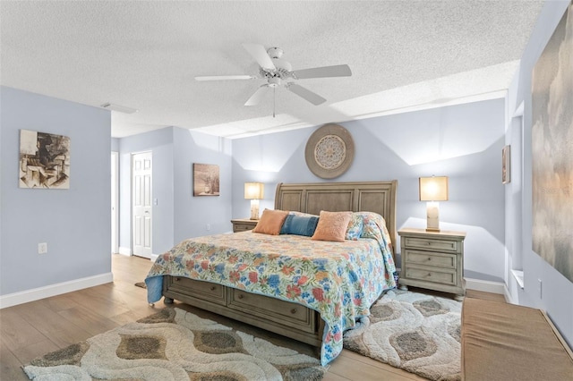 bedroom featuring a textured ceiling, light wood-type flooring, and ceiling fan