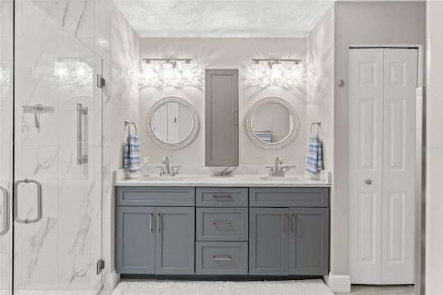 bathroom with a textured ceiling, vanity, and walk in shower